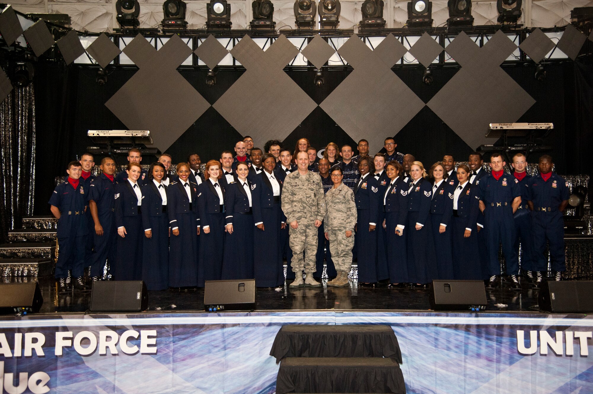 PETERSON AIR FORCE BASE, Colo. – Col. Douglas Schiess, 21st Space Wing commander, and Chief Master Sgt. Idalia Peele, 21st Space Wing command chief, pose for a photograph with the Tops in Blue performers after their show at Hangar 140, July 1, 2015. The all-active duty U.S. Air Force special unit is made up of performers who have mastered their skills in vocals, instrument, choreography and staging to tour to 20 countries, performing 75 shows in seven months. (U.S. Air Force photo by Senior Airman Tiffany DeNault)