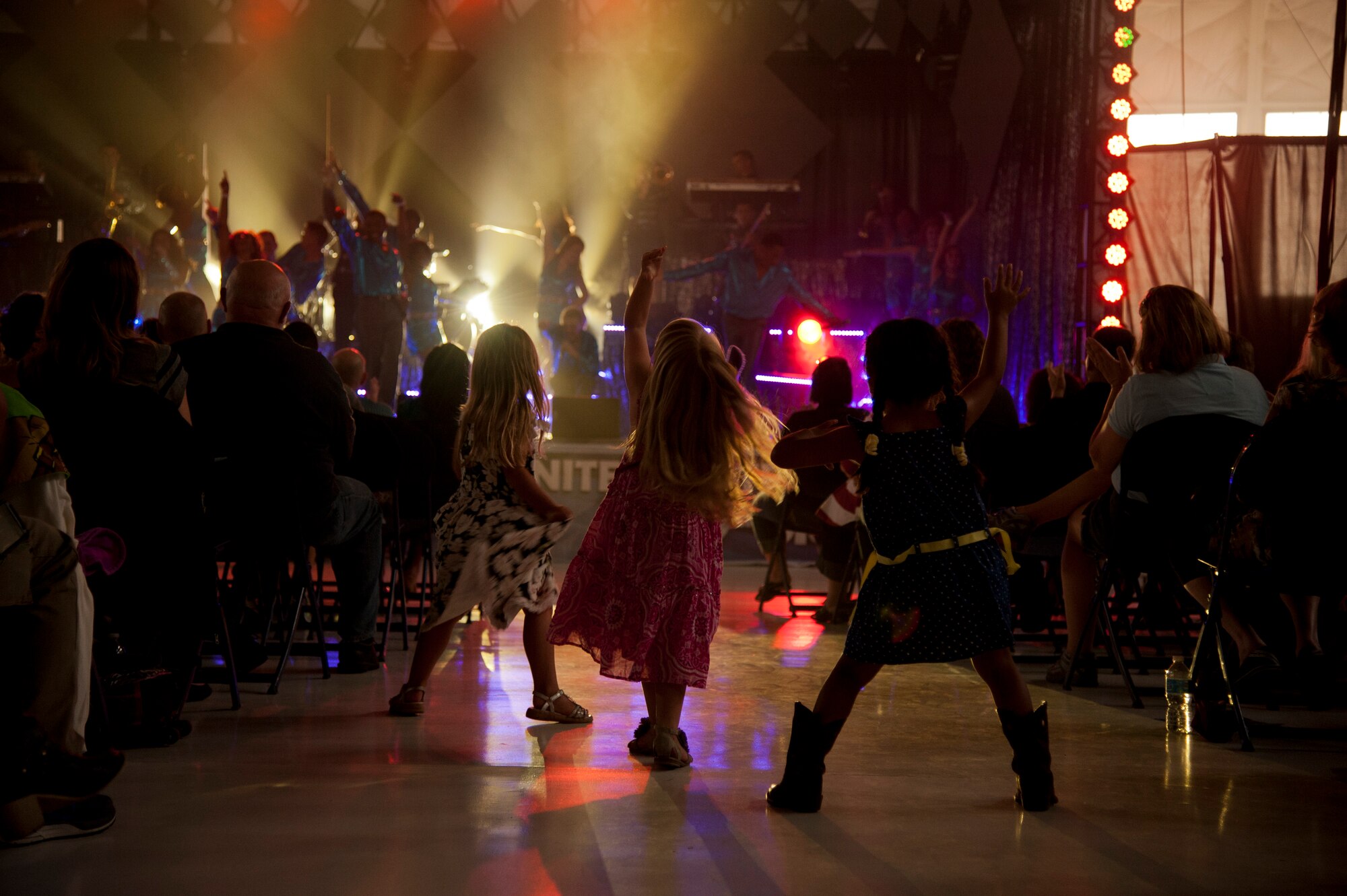 PETERSON AIR FORCE BASE, Colo. – Children dance in the aisle during the Tops in Blue performance at Hangar 140, July 1, 2015. The Tops in Blue performers travel to 20 countries putting on 75 shows in seven months, promoting community relations, recruiting efforts and serving as ambassadors for the United States and the U.S. Air Force. (U.S. Air Force photo by Senior Airman Tiffany DeNault)