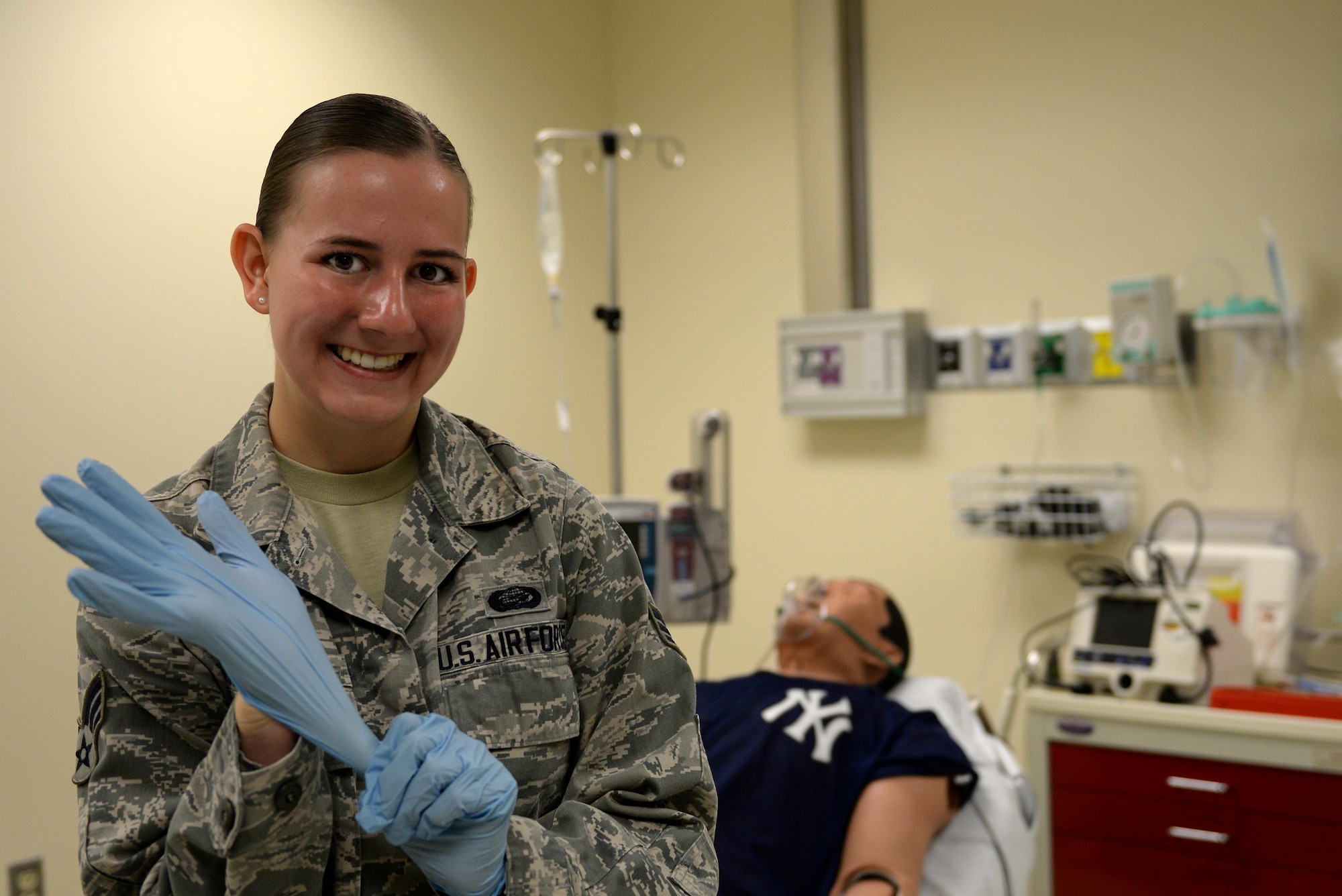 Senior Airman Alyssa Johnson, 81st Force Support Squadron force management journeyman, puts on gloves in the Keesler Medical Simulation and Clinical Skills Center, July 7, 2015, Keesler Air Force Base, Miss. Johnson, who has been stationed at Keesler for three years, was selected for the Air Force Nurse Enlisted Commissioning Program and will begin school Aug. 24, 2015 at the University of West Florida, Pensacola, Fla. (U.S. Air Force photo by Airman 1st Class Duncan McElroy)
