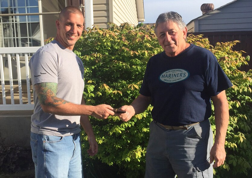 Staff Sgt. Rich Johnson, 92nd Air Refueling Squadron boom operator, returns Joseph Hartz’s missing wallet to his son, Nick Merrill, June 21, 2015, in Spokane, Wash. Johnson contacted Merrill and made arrangements to drive the wallet personally over to his home to guarantee the precious memories contained in the wallet were returned to the family. (Courtesy photo)