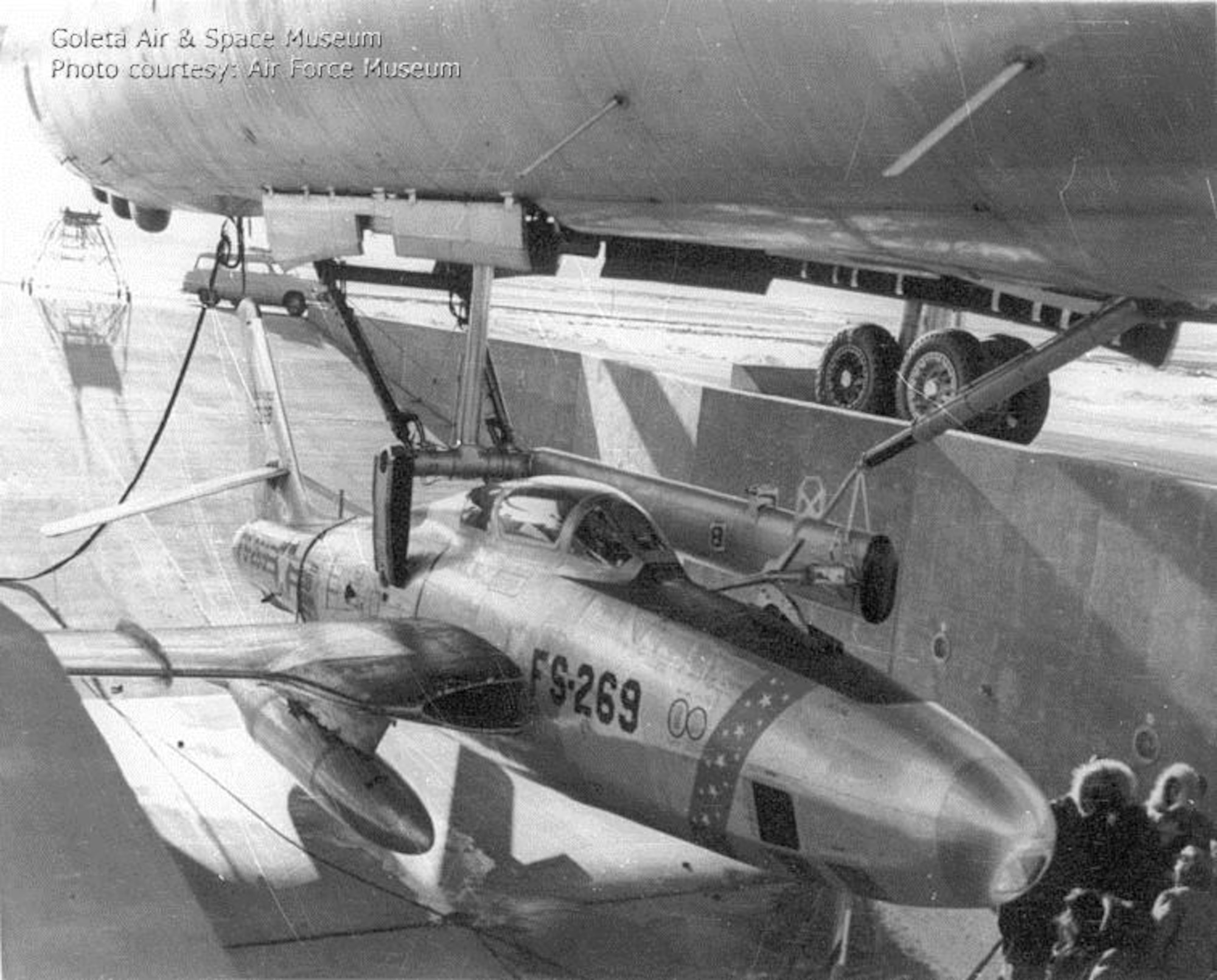 FICON RBF-84K Thunderflash, 52-7269, is lowered from the bomb bay of GRB-36D Peacemaker, 49-2696, at Fairchild Air Force Base, Wash., following an emergency night retrieval on Dec. 12, 1955. The parasite pilot suffered a partial hydraulic system failure but succeeded in hooking onto the trapeze. Post-flight inspection revealed he had turned off his own hydraulic system due to the distractions of approaching the trapeze. (U.S. Air Force photo)