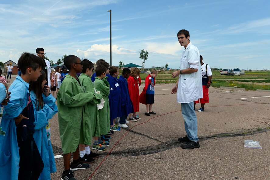 Monahan LLC Science Camp staff member Sam Birchenough (right) gives instructions to Schriever School Age Program students prior to their rocket launch Thursday July 2, 2015 at Schriever Air Force Base, Colorado. The launch was the final activity for the SAPs Science Camp, which, as part of the response to a mock meteorite strike, gave students the opportunity to learn about the scientific method by creating a theory and hypothesis for the strike, build robots in order to collect samples in a radioactive environment and dissect frogs to determine if there was a biological event. (U.S. Air Force photo/Christopher DeWitt)