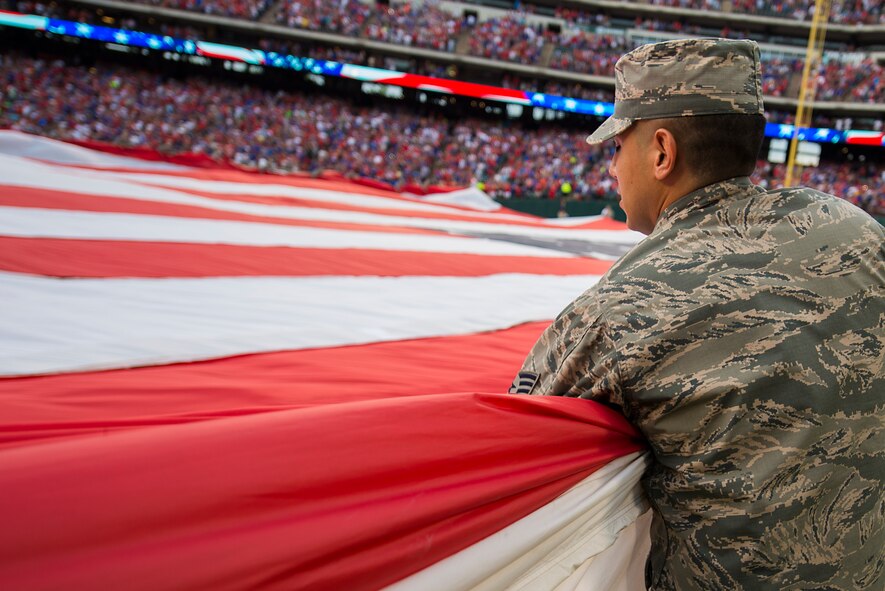U.S. Air Force Tech. Sgt. Richard Sandoval from the 344th Recruiting Squadron, Texarkana Texas, helps hold a giant U.S. Flag for an enlistment ceremony during the opening of the Rangers game in Arlington, Texas, July 4, 2015. More than 60 Airmen from Sheppard volunteered with the 344th Recruiting Squadron to help unfurl the flag for approximately 150 new Air Force enlistees who swore-in during the game. (U.S. Air Force photo by Senior Airman Kyle Gese/Released)
