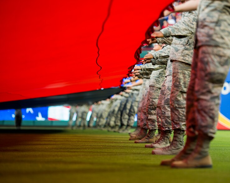 U.S. Air Force Airmen from Sheppard Air Force Base, Texas, help hold a giant U.S. Flag for an enlistment ceremony during the opening of the Rangers game in Arlington, Texas, July 4, 2015. More than 60 Airmen from Sheppard volunteered with the 344th Recruiting Squadron to help unfurl the flag for approximately 150 new Air Force enlistees who swore-in during the game. (U.S. Air Force photo by Senior Airman Kyle Gese/Released)
