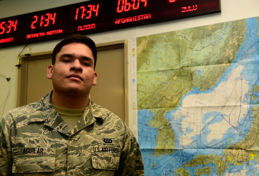 U.S. Air Force Airman 1st Class Israel Aguilar, 35th Operations Support Squadron combat intelligence cell analyst, poses in front of a map and time zone clock at Misawa Air Base, Japan, July 7, 2015. Aguilar informs leadership of possible threats to the 35th Fighter Wing’s mission to ensure its safety. (U.S. Air Force photo by Airman 1st Class Jordyn Fetter/Released)