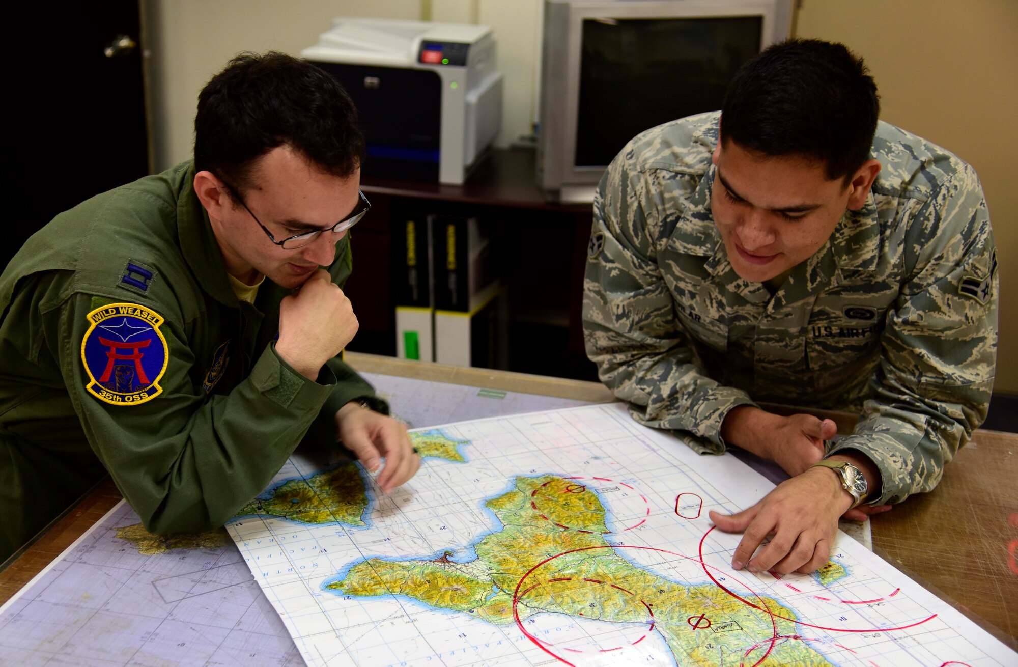 U.S. Air Force Airman 1st Class Aguilar, 35th Operations Support Squadron combat intelligence cell analyst, gives a pre-mission brief to U.S. Air Force Capt. David Hernandez, 35 OSS weapons and tactics officer, at Misawa Air Base, Japan, July 7, 2015. These briefs explain the threats in a mission’s area of responsibility. (U.S. Air Force photo by Airman 1st Class Jordyn Fetter/Released)