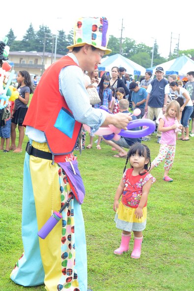 A clown shapes a pair of balloon wings for a child during Celebrate America at Yokota Air Base, Japan, July 2, 2015. Yokota residents gathered together to celebrate Independence Day with live music, food and fireworks. (U.S. Air Force photo by Airman 1st Class David C. Danford/Released)