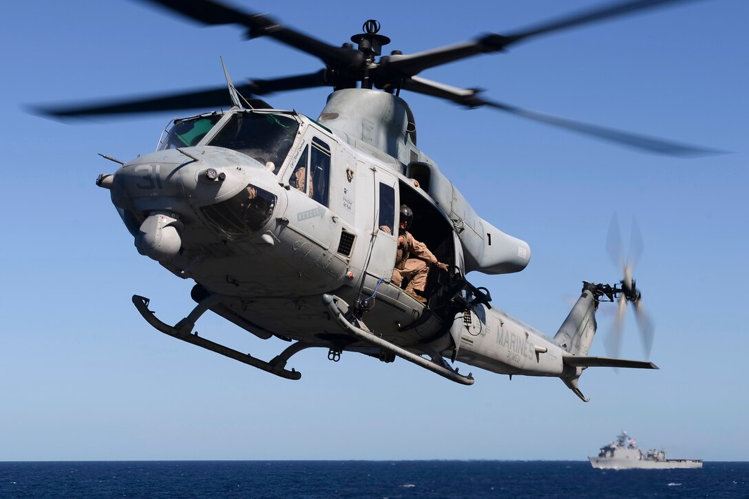 A UH1Y Huey helicopter flies ahead of the USS Ashland during an