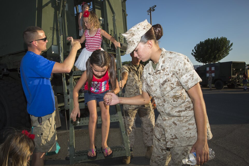 Pfc. Megan Ripley, motor transport operator, Marine Wing Support Squadron 374, helps Melany Cahill, 7, niece of Starr Vassion, native of Twentynine Palms, Calif., as she dismounts from a Medium Tactical Vehicle Replacement during the Twentynine Palms Independence Day celebration at Luckie Park, July 4, 2015. The event was hosted by the City of Twentynine Palms. (Official Marine Corps photo by Pfc. Levi Schultz/Released)
