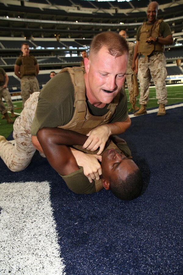 Master Gunnery Sgt. Beutz, (left), ground fights with Sgt. Jordan Johnson, legal chief and separations NCO for Headquarters Company, 14th Marine Regiment, during a special physical training session held at the Dallas Cowboys stadium in Arlington, Texas, July 1, 2015.  The regiment's Commanding Officer, Col. Joseph Russo, lead more than 40 of his Marines on a 3-mile run inside the stadium to build camaraderie and teamwork to help them focus on his vision of the Marine Corps' Expeditionary Force 21, the planning concept to develop the Corps over the next 10 years. Russo came up with the idea to use Cowboys Stadium as a training location because he said  he understands what an honor it is to lead such an incredible group of Marines such as those in the regiment so he wanted to do something different and unique for them to thank them for all of their hard work and dedication to the unit and the Corps. (U.S. Marine Corps photo by Master Sgt. Katesha Washington)