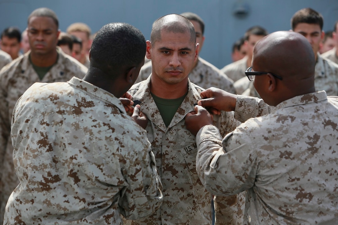 GULF OF ADEN (July 1, 2015) U.S. Marine Master Sgt. Jomoore Toney, far left, and 1st Sgt. Sasha Dix, far right, pin new rank insignia onto Gunnery Sgt. Carlos Gonzalez during his promotion ceremony on the forecastle of the amphibious transport dock ship USS Anchorage (LPD 23). All are members of Battalion Landing Team 3rd Battalion, 1st Marine Regiment, 15th Marine Expeditionary Unit. Anchorage is part of the Essex Amphibious Ready Group and, with the embarked 15th Marine Expeditionary Unit, is deployed in support of maritime security operations and theater security cooperation efforts in the U.S. 5th Fleet area of operations. (U.S. Marine Corps photo by Sgt. Steve H. Lopez/ Released)