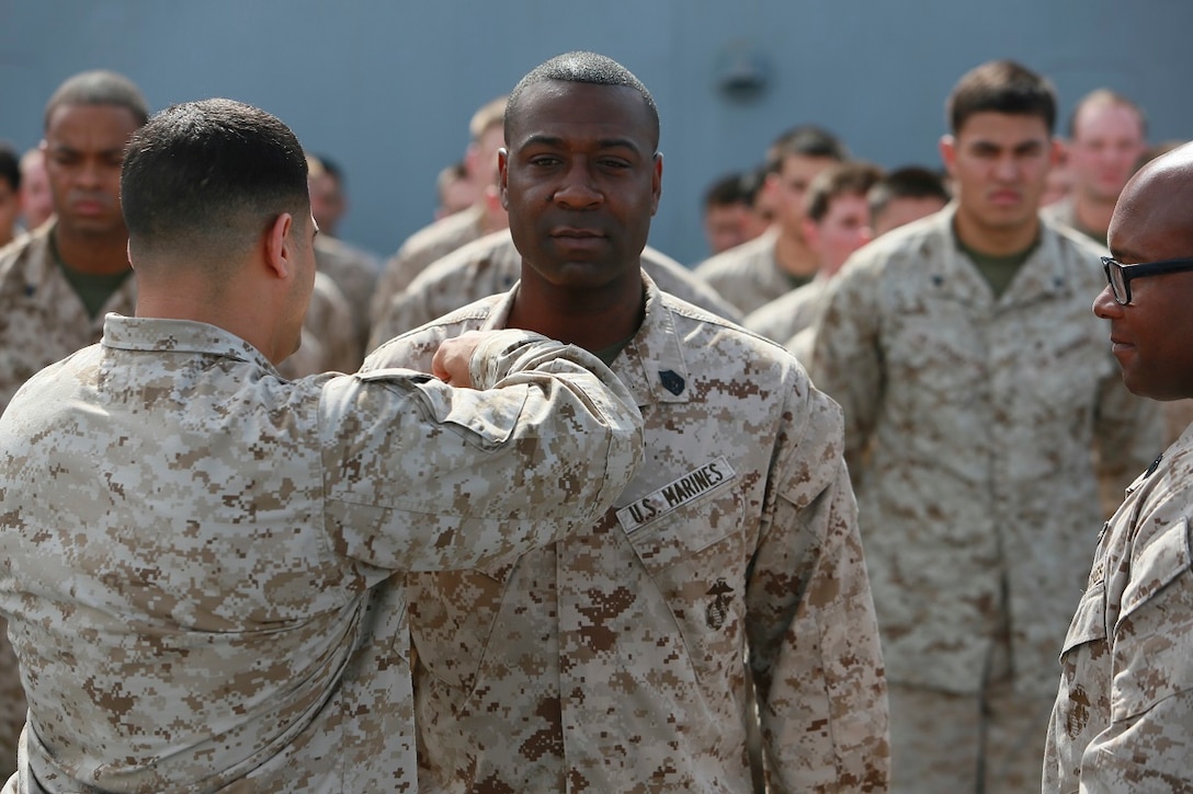 GULF OF ADEN (July 1, 2015) U.S. Marine Capt. Edward Gonzales pins new rank insignia onto Gunnery Sgt. Michael Washington during his promotion ceremony on the forecastle of the  amphibious transport dock ship USS Anchorage (LPD 23). Washington is the company gunnery sergeant for Headquarters and Service Company, Battalion Landing Team 3rd Battalion, 1st Marine Regiment, 15th Marine Expeditionary Unit. Anchorage is part of the Essex Amphibious Ready Group and, with the embarked 15th Marine Expeditionary Unit, is deployed in support of maritime security operations and theater security cooperation efforts in the U.S. 5th Fleet area of operations.  (U.S. Marine Corps photo by Sgt. Steve H. Lopez/ Released)
