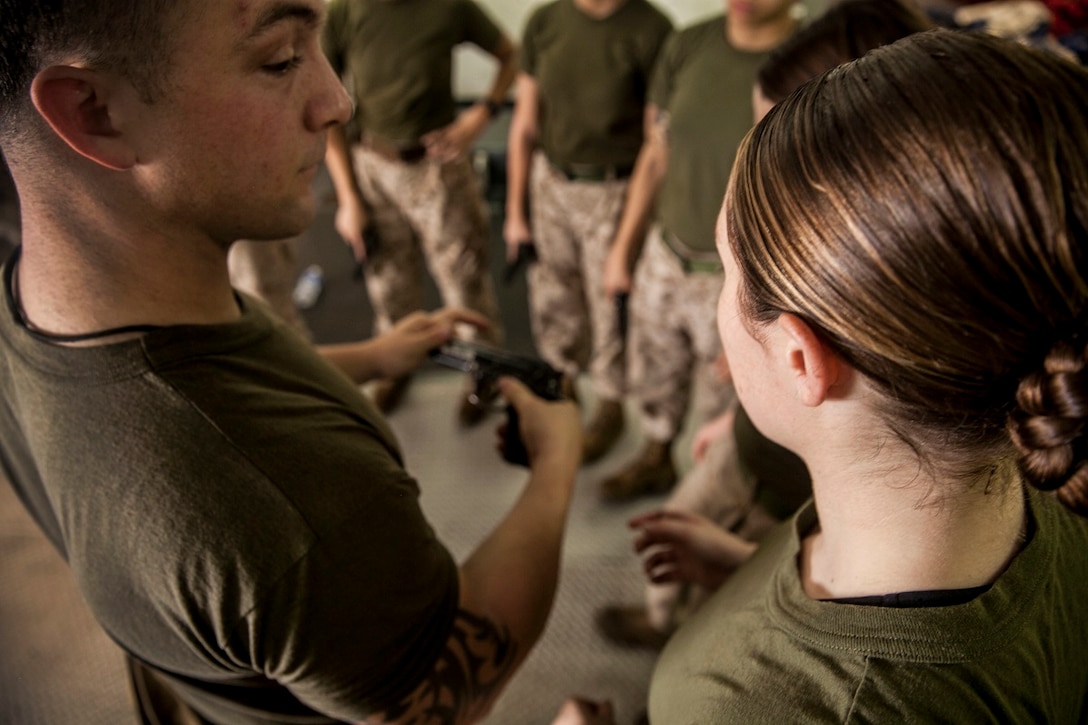 U.S. Marine Sgt. Daniel Mullis, left, teaches nomenclature and handling techniques for the M9 Beretta pistol during a female engagement team class aboard the amphibious assault ship USS Essex (LHD 2). Mullis is a member of the 15th Marine Expeditionary Unit’s Maritime Raid Force. The Marines are participating in a week-long screener to assess their knowledge of skills such as marksmanship, detainee handling, patrolling, and teaching skills. The 15th MEU is embarked on the Essex Amphibious Ready Group and deployed to maintain regional security in the U.S. 5th Fleet area of operations. (U.S. Marine Corps photo by Cpl. Elize McKelvey/ Released)