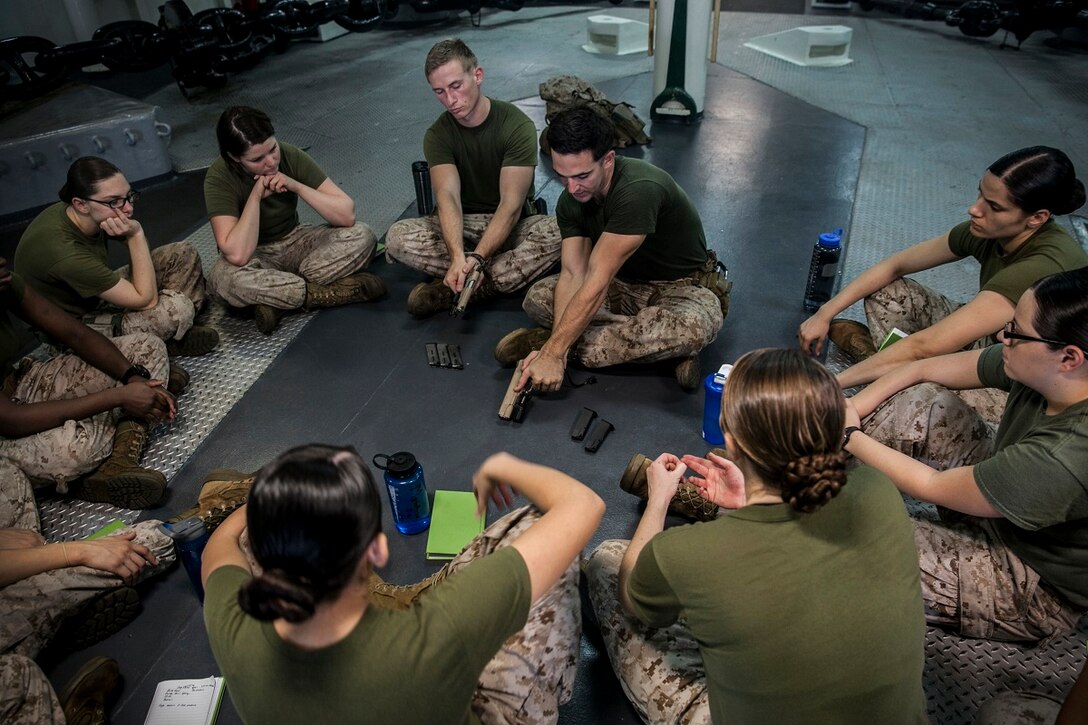U.S. Marine Sgt. Sean Bernstein, middle, teaches nomenclature and handling techniques for the M45 1911 A1 pistol during a female engagement team class aboard the amphibious assault ship USS Essex (LHD 2). Bernstein is a member of the 15th Marine Expeditionary Unit’s Maritime Raid Force. The Marines are participating in a week-long screener to assess their knowledge of skills such as marksmanship, detainee handling, patrolling, and teaching skills. The 15th MEU is embarked on the Essex Amphibious Ready Group and deployed to maintain regional security in the U.S. 5th Fleet area of operations. (U.S. Marine Corps photo by Cpl. Elize McKelvey/ Released)