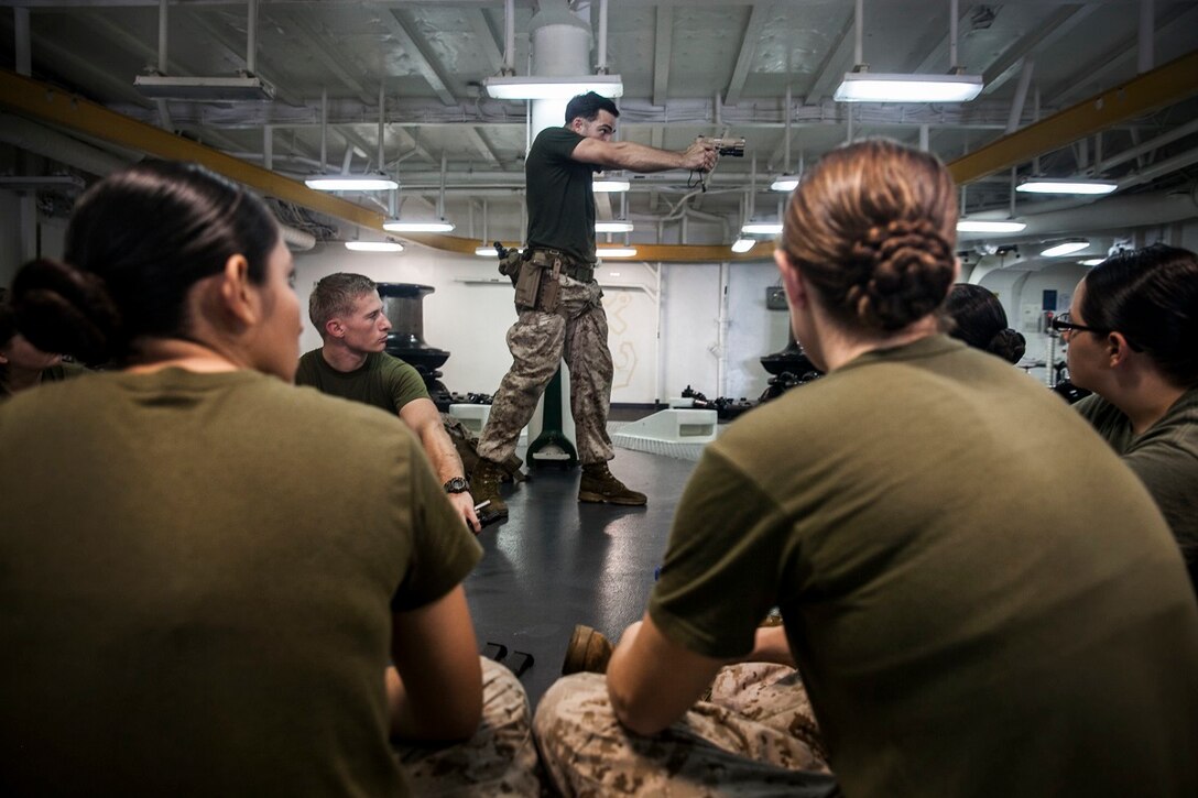 U.S. Marine Sgt. Sean Bernstein, middle, teaches nomenclature and handling techniques for the M45 1911 A1 pistol during a female engagement team class aboard the amphibious assault ship USS Essex (LHD 2). Bernstein is a Member of the 15th Marine Expeditionary Unit’s Maritime Raid Force. The Marines are participating in a week-long screener to assess their knowledge of skills such as marksmanship, detainee handling, patrolling, and teaching skills. The 15th MEU is embarked on the Essex Amphibious Ready Group and deployed to maintain regional security in the U.S. 5th Fleet area of operations. (U.S. Marine Corps photo by Cpl. Elize McKelvey/ Released)