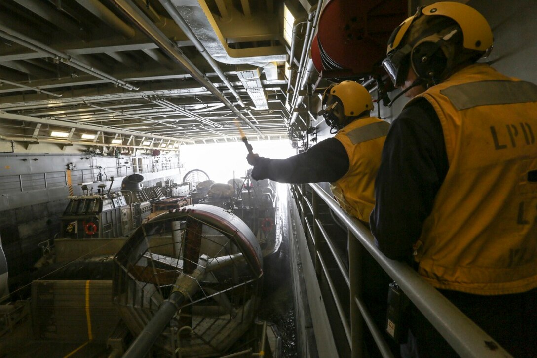 GULF OF ADEN (July 2, 2015) U.S. Sailors signal a landing craft, air cushion to launch in the well deck of the amphibious transport dock USS Anchorage (LPD 23).  The Anchorage is part of the Essex Amphibious Ready Group and, with the embarked 15th Marine Expeditionary Unit, is deployed in support of maritime security operations and theater security cooperation efforts in the U.S. 5th Fleet area of operations. (U.S. Marine Corps photo by Sgt. Jamean Berry/Released)