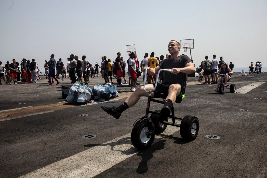 GULF OF ADEN (July 4, 2015) U.S. Marines and Sailor with the 15th Marine Expeditionary Unit and Essex Amphibious Ready Group, have fun on tricycles during a steel beach picnic on the flight deck of the amphibious assault ship USS Essex (LHD 2).The event built morale among the 15th MEU and with Sailors from the Essex ARG. The 15th MEU is embarked on the Essex ARG and deployed to maintain regional security in the U.S. 5th Fleet area of operations. (U.S. Marine Corps photo by Cpl. Elize McKelvey/ Released)
