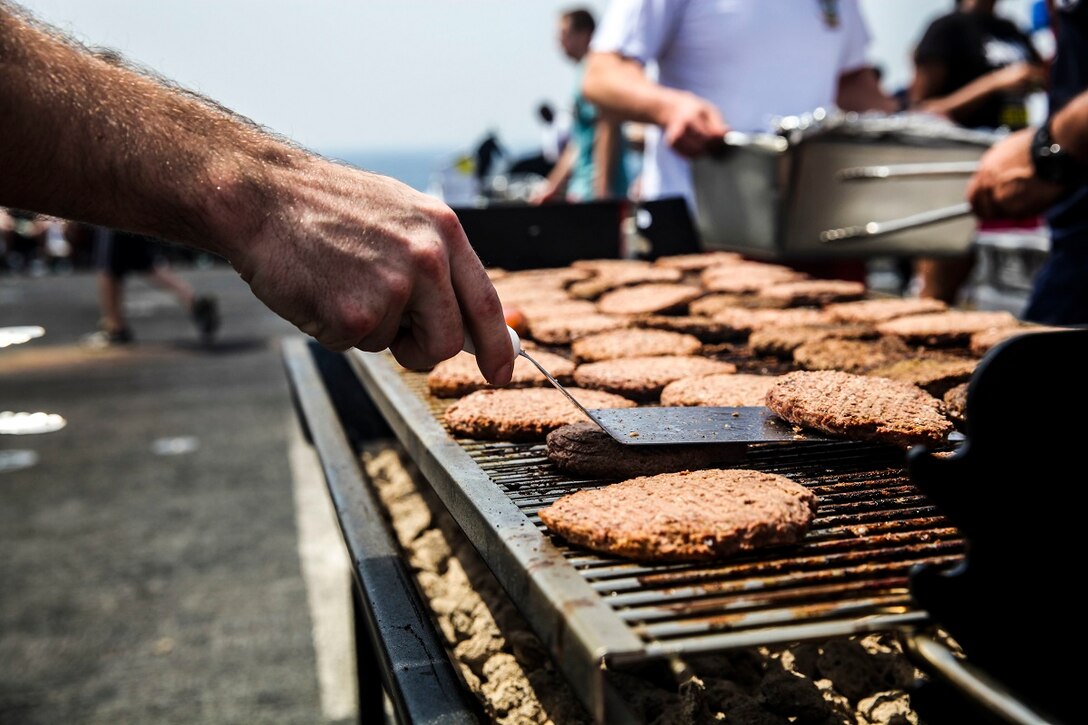 GULF OF ADEN (July 4, 2015) U.S. Marines and Sailor with the 15th Marine Expeditionary Unit and Essex Amphibious Ready Group, grill out during a steel beach picnic on the flight deck of the amphibious assault ship USS Essex (LHD 2). The event built morale among the 15th MEU and with Sailors from the Essex ARG. The 15th MEU is embarked on the Essex ARG and deployed to maintain regional security in the U.S. 5th Fleet area of operations. (U.S. Marine Corps photo by Cpl. Elize McKelvey/ Released)