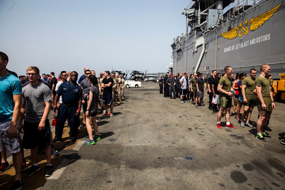 GULF OF ADEN (July 4, 2015) U.S. Marines and Sailors with the 15th Marine Expeditionary Unit and Essex Amphibious Ready Group, wait for food during a steel beach picnic on the flight deck of the amphibious assault ship USS Essex (LHD 2).The event built morale among the 15th MEU and with Sailors from the Essex ARG. The 15th MEU is embarked on the Essex ARG and deployed to maintain regional security in the U.S. 5th Fleet area of operations. (U.S. Marine Corps photo by Cpl. Elize McKelvey/ Released)