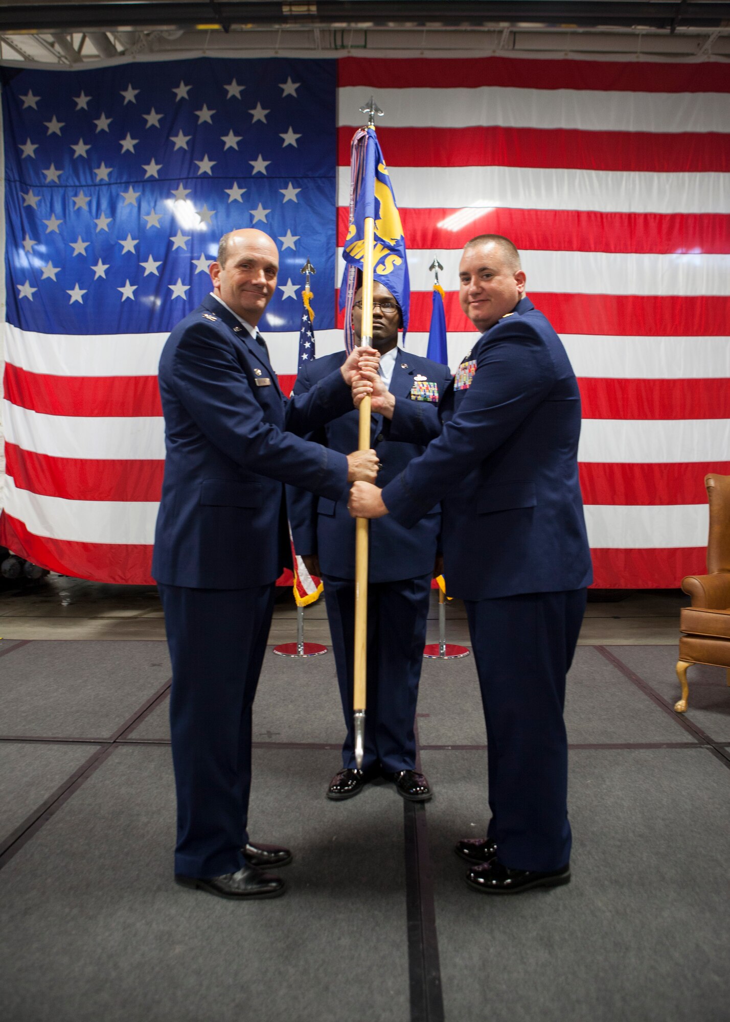Col. Trevor Flint, 90th Maintenance Group commander, passes the guidon to Maj. Jeremy Russell, 90th Missile Maintenance Squadron commander, during the 90th MMXS assumption of command July 8, 2015. The ceremony signified the transition of command from Maj. Richard Fongemie to Russell. (U.S. Air Force photo by Lan Kim)