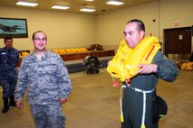 Tech Sgt. John Cavazos (left), aircrew flight equipment technician with 433rd Operations Support Squadron successfully shows Maj. Carlos Esteban (center), a pilot with the Colombian Air Force, how to use a flotation device at Joint Base San Antonio-Lackland, Texas, July 8, 2015. Esteban is a student from the Inter-American Air Forces Academy (IAAFA). (U.S. Air Force photo/Tech Sgt. Carlos J. Trevino)