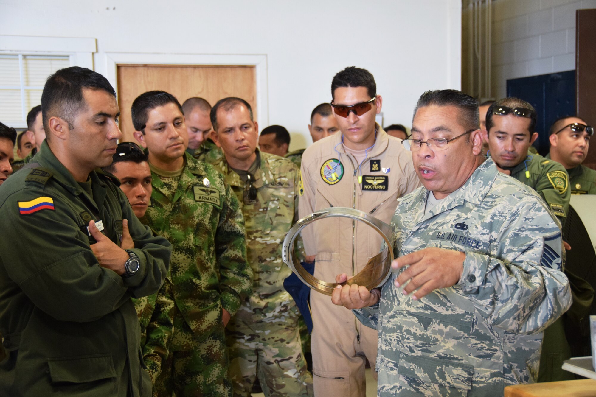 Master Sgt. Fidencio “Pete” Ramon (right) , metal technologies shop chief, explains how a discontinued part is manufactured for the C-5A Galaxy aircraft to students from Inter-American Air Forces Academy at Joint Base San Antonio-Lackland, Texas on July 8, 2015, during a tour of the 433rd Maintenance Squadron. The Alamo Wing's C-5A Galaxy fleet is over forty years old, therefore aircraft parts cannot be purchased through traditional supply lines, because each part has a unique shape and profile, parts are custom made in the shop. (U.S. Air Force photo/Tech Sgt. Carlos J. Trevino)