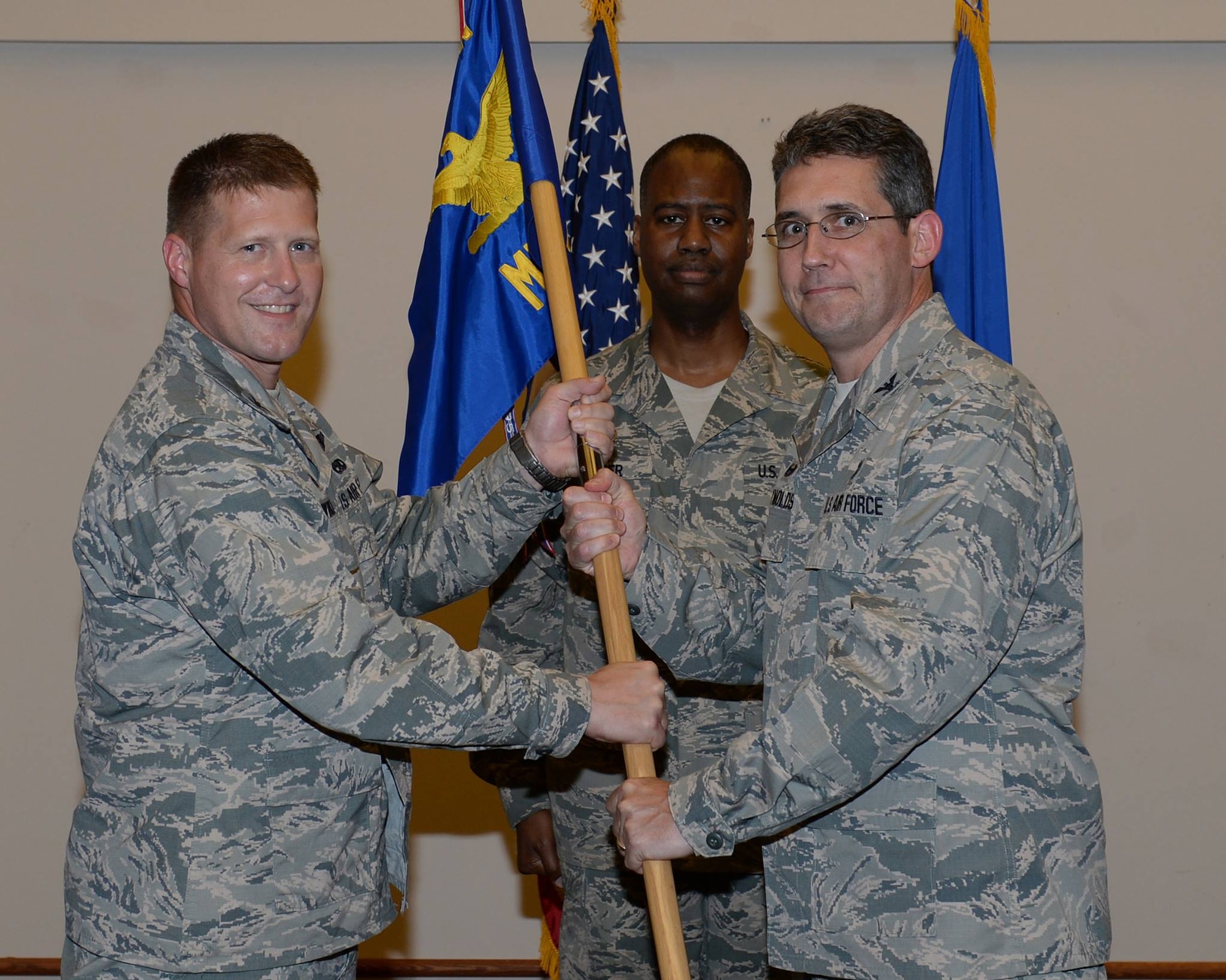 U.S. Air Force Col. Michael Winkler, the 354th Fighter Wing commander, passes the 354th Medical Group guidon to Col. William Reynolds, the new 354th MDG commander, June 29, 2015, at Eielson Air Force Base, Alaska. Col. Joseph Narrigan, the outgoing group commander, will move on to Eglin Air Force Base, Fla. (U.S. Air Force photo by Staff Sgt. Shawn Nickel/Released)