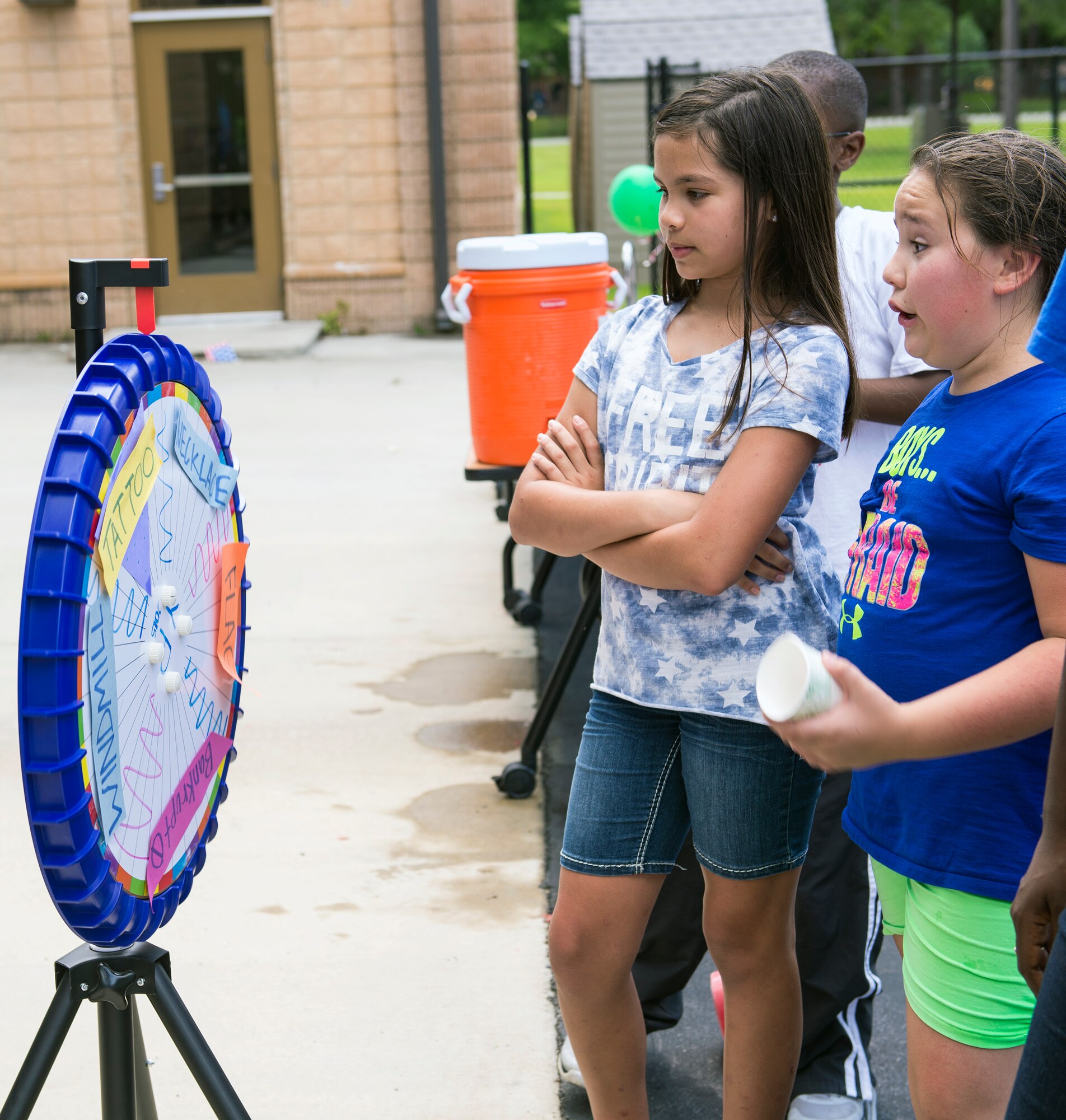 Isabella Shrader, left, daughter of U.S. Air Force Senior Master Sgt. Kimberly Waldrop, 23d Equipment Maintenance Squadron, waits for a prize wheel to stop during the July Jamboree, July 6, 2015, at Moody Air Force Base, Ga. Participants won prizes consisting of tattoos, necklaces, windmills, and flags. (U.S. Air Force photo by Airman Greg Nash/Released)