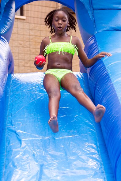 Naiya Wade, daughter of U.S. Air Force Tech. Sgt. Michaela Maximin, 23d Force Support Squadron, jumps onto a slip-and-slide bounce house during the July Jamboree, July 6, 2015, at Moody Air Force Base, Ga. The event provided outdoor activities for youth program participants to interact with other attendees and staff. (U.S. Air Force photo by Airman Greg Nash/Released)