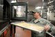 Staff Sgt. Casey Barron, 375 Force Support Squadron Shift Leader and Cook, places fish into an oven to be cooked in the Nightingale Inn Dining Facility June 30, 2015 at Scott Air Force Base, Illinois. Barron’s daily tasks include training and supervising the Airmen cooking to ensure customers get the best quality food. (U.S. Air Force photo/Senior Airman Joshua Eikren)
