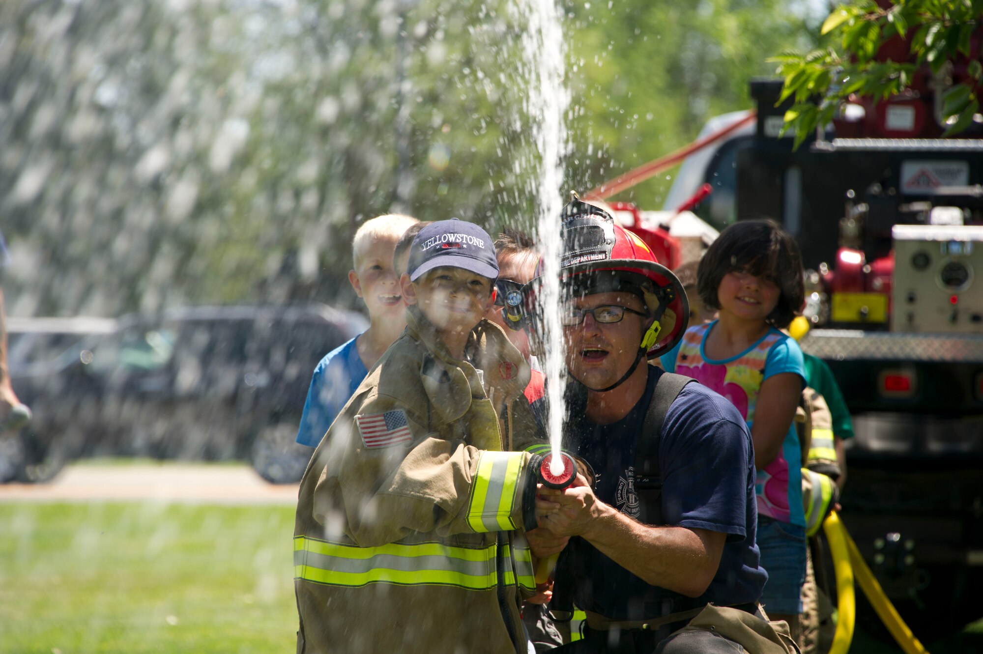 Tech. Sgt. Jacob Wallace, 92nd Civil Engineer Squadron firefighter, assists children Fairchild's Youth Summer Program by aiming a fire hose at a target during a summer youth fire prevention camp, July 1, 2015, at Fairchild Air Force Base, Wash. The children went through a gauntlet of team building obstacles that showed the importance of team work. (U.S. Air Force photo/Airman 1st Class Nicolo J. Daniello)