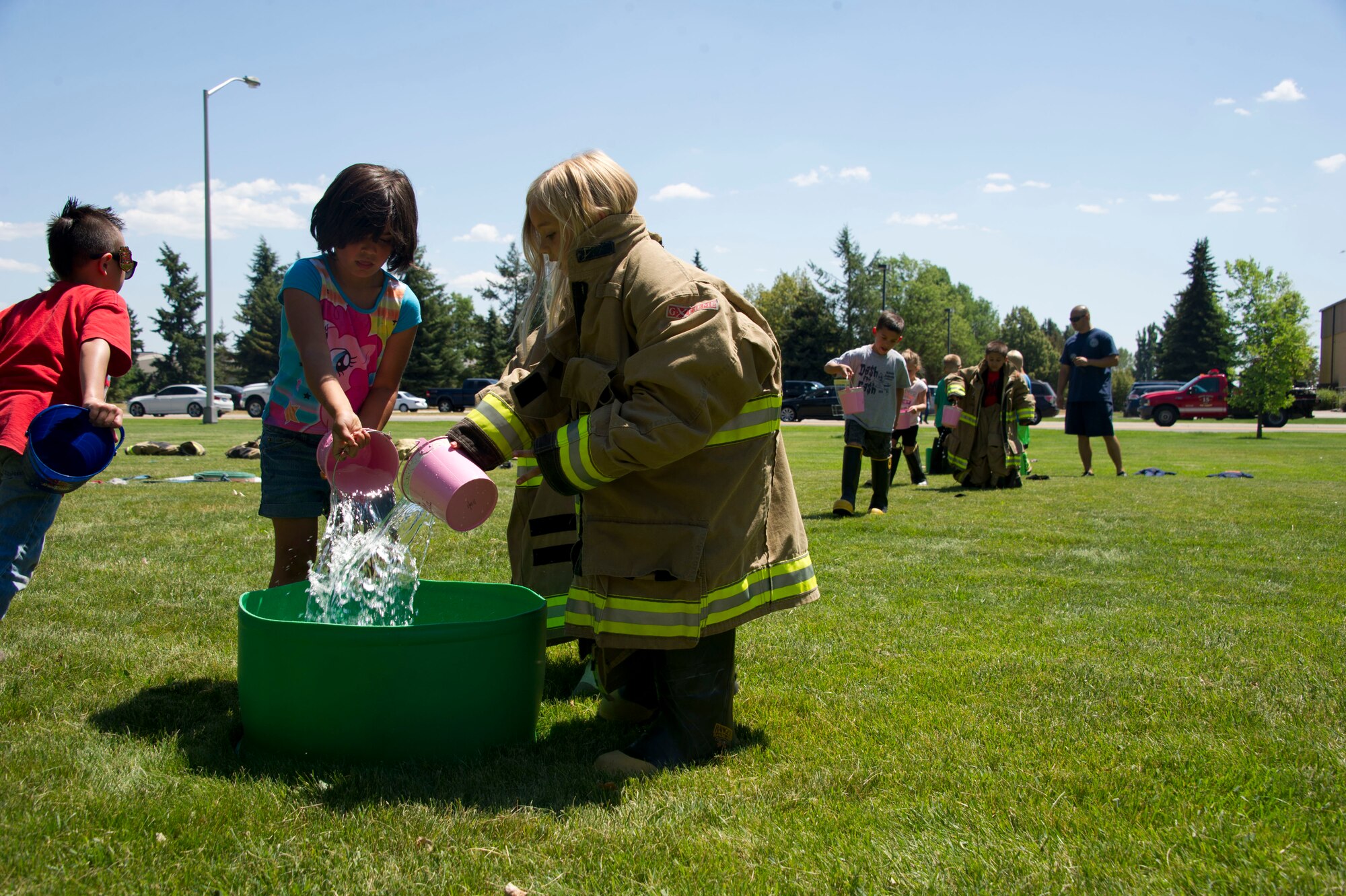 Children from Fairchild's Youth Summer Program pour water into a bucket during a summer youth fire prevention camp, July 1, 2015, at Fairchild Air Force Base, Wash. The children re-enacted techniques firefighters used before having the fire hose, with a pail and a bucket of water. (U.S. Air Force photo/Airman 1st Class Nicolo J. Daniello)