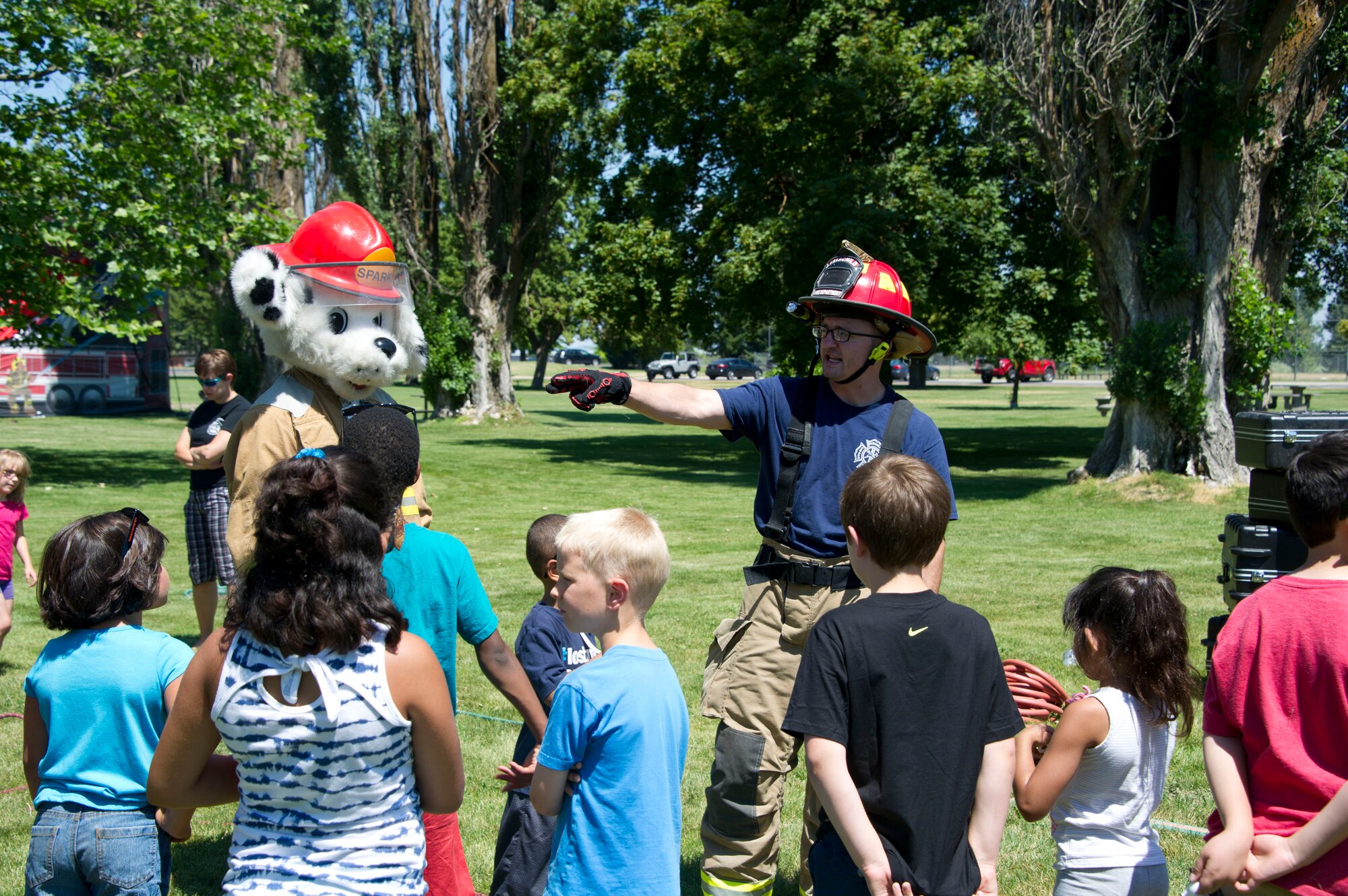 Sparky the fire dog and Tech. Sgt. Jacob Wallace, 92nd Civil Engineer Squadron firefighter, speak with children from Fairchild's Youth Summer Program during a summer youth fire prevention camp, July 1, 2015, at Fairchild Air Force Base, Wash. The children listened to instructions before taking part in the firefighter themed obstacle course. (U.S. Air Force photo/Airman 1st Class Nicolo J. Daniello)