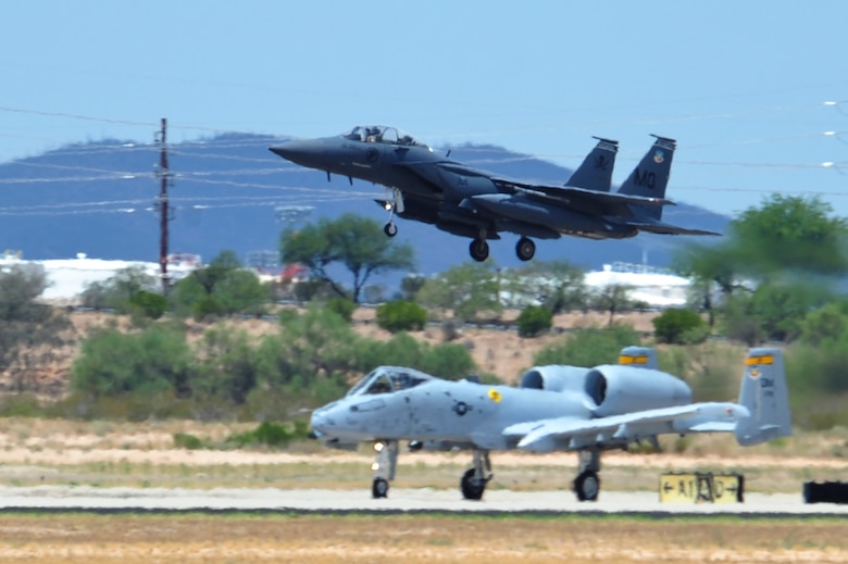 An F-15SG from the 428th Fighter Squadron at Mountain Home Air Force Base, Idaho, flies over an A-10 Thunderbolt II while approaching the runway at Davis-Monthan Air Force Base, Ariz., July 7, 2015. Ten of the jets arrived to train at D-M until Aug. 24 while MHAFB's runway is closed for maintenance. (U.S. Air Force photo by Airman 1st Class Chris Drzazgowski/Released)