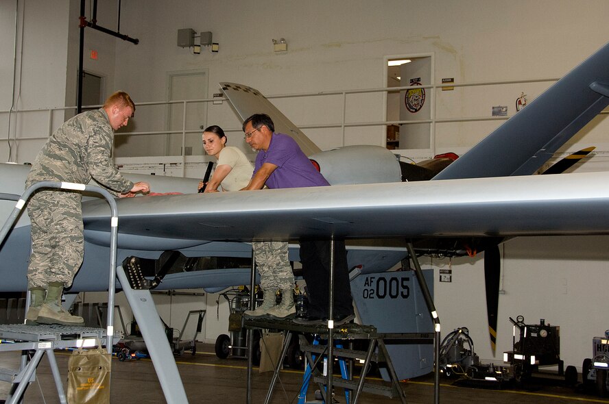 Phillip Castro, 362nd Training Squadron Aircraft maintenance Instructor, instructs Airman Christian Swanson and Airman 1st Class Jessica Locci on performing brake bleed and brake system operational procedures on MQ-9 Reaper Sheppard Air Force Base, Texas Jul. 07, 2015. Students learn the important of the individual system components and ensure all safety checks are performed to the highest of standards. The course is intended to train Airmen how to perform safe maintenance on the Ground Control Station and MQ-9 Reaper. (U.S. Air Force photo by Danny Webb/Released)