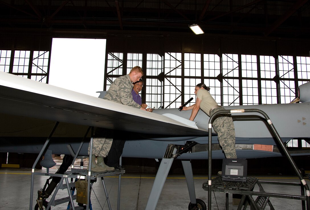 Phillip Castro, 362nd Training Squadron Aircraft maintenance Instructor, instructs Airman Christian Swanson and Airman 1st Class Jessica Locci on performing brake bleed and brake system operational procedures on MQ-9 Reaper Sheppard Air Force Base, Texas Jul. 07, 2015. Students learn the important of the individual system components and ensure all safety checks are performed to the highest of standards. The course is intended to train Airmen how to perform safe maintenance on the Ground Control Station and MQ-9 Reaper. (U.S. Air Force photo by Danny Webb/Released)