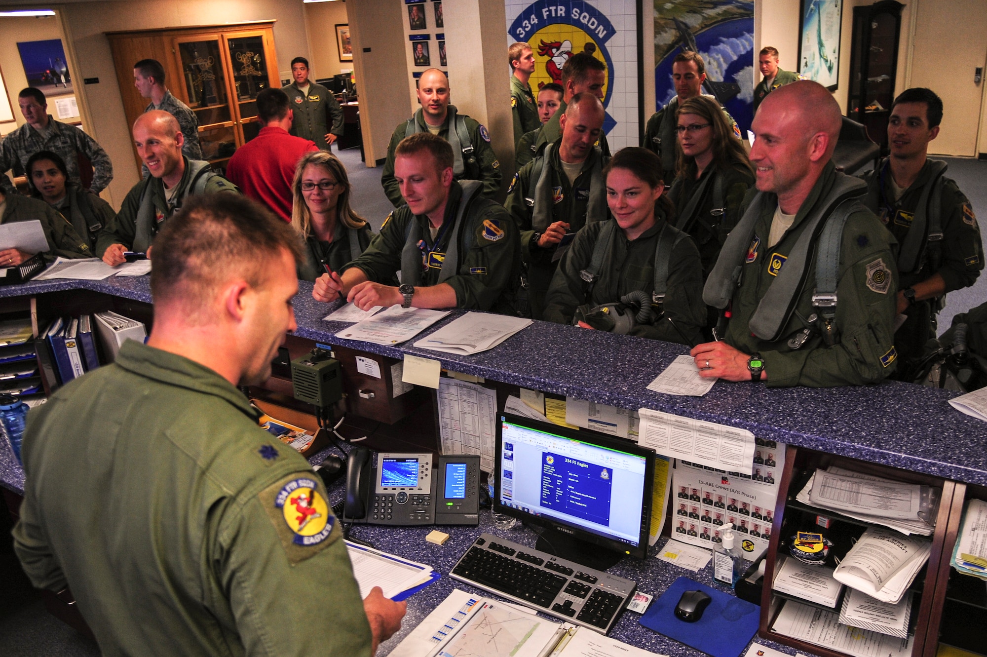 Lt. Col. Eric Schmidt, 334th Fighter Squadron director of operations, delivers a step brief as part of a spouse orientation, July 1, 2015, at Seymour Johnson Air Force Base, North Carolina. Schmidt delivered the weather expectancies as well as other flight logistics to ensure all aircrew were fully prepared for their mission. (U.S. Air Force photo/Senior Airman Brittain Crolley)