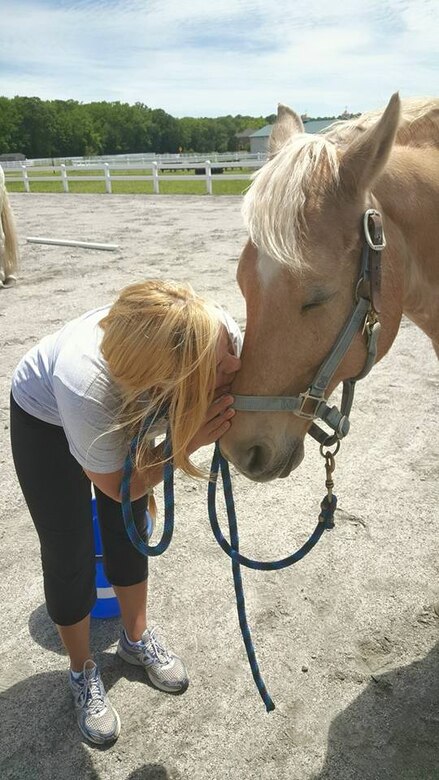 U.S. Air Force Airman 1st Class Haley Benson, 633rd Medical Operations Squadron behavioral health technician, kisses a horse at Equi-Kids and Equi-Vets, a therapeutic riding center in Virginia Beach, Va., May 29, 2015. As a part of helping other better themselves, Benson works with children with disabilities and veterans who may suffer with Post-Traumatic Stress Disorder through the therapy center.  (Courtesy photo)