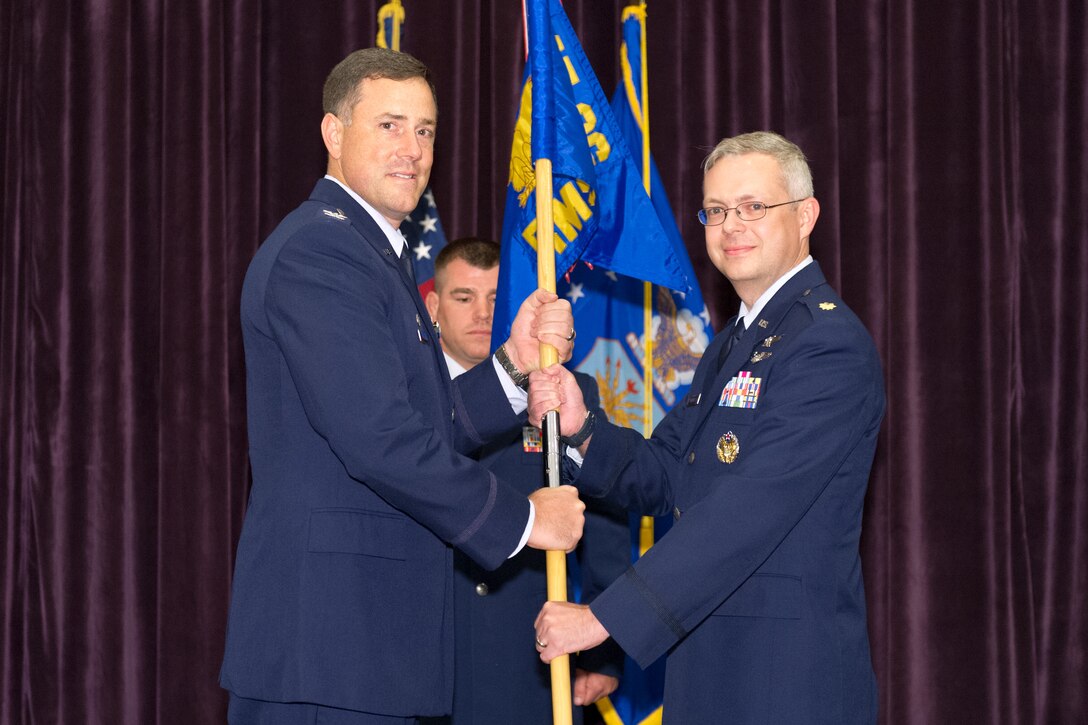 Col. Thomas Falzarano, 45th Operations Group commander, left, presents Maj. Elwood Waddell, 45th Range Management Squadron commander, with the 45th RMS guidon during a change of command ceremony July 1, 2015, at Patrick Air Force Base, Fla. Changes of command are a military tradition representing the transfer of responsibilities from the presiding officials to the upcoming official. (U.S. Air Force photo/Cory Long) (Released)