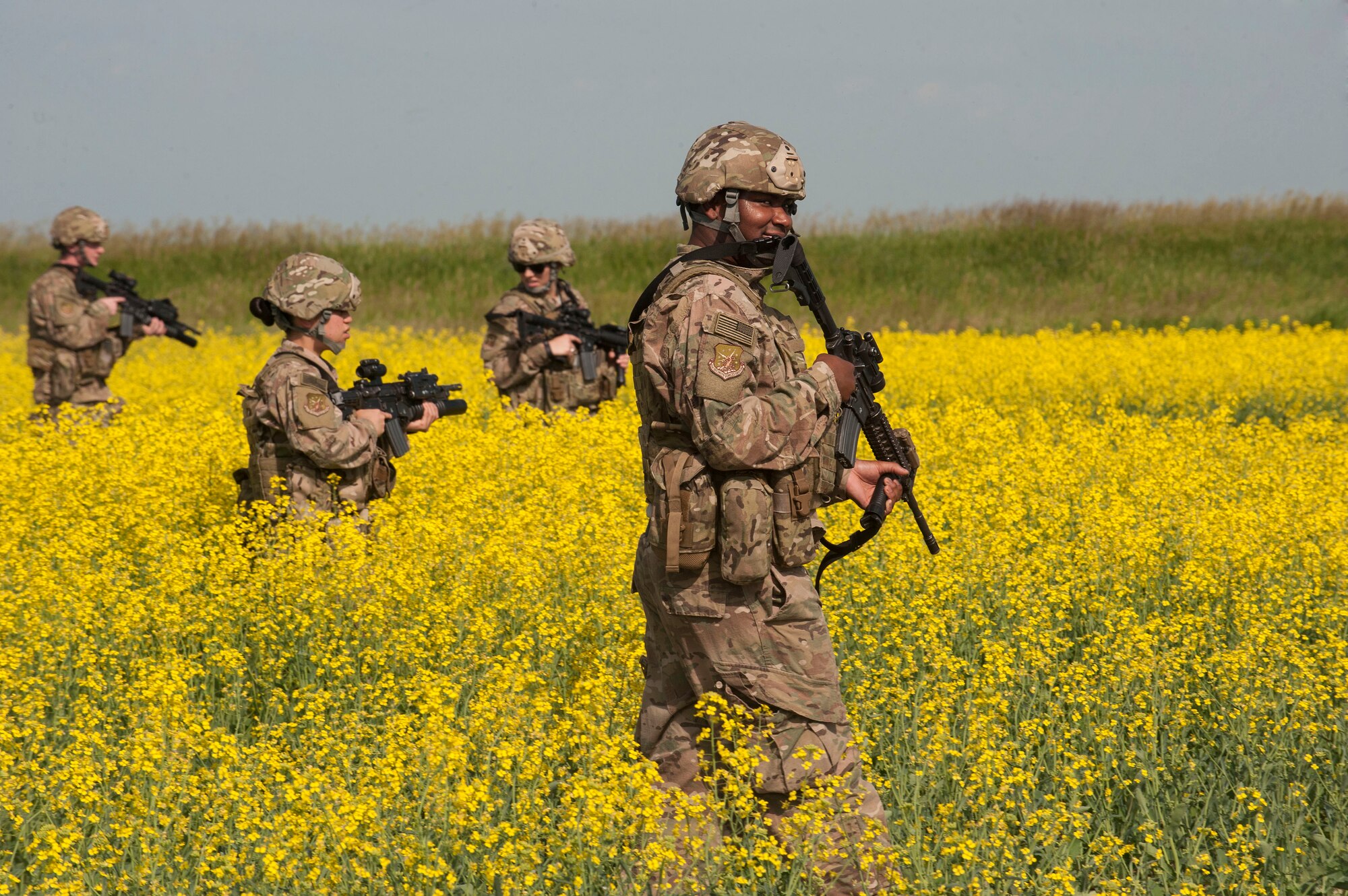 91st Missile Wing Security Forces Group members patrol through a canola field during an exercise area near Donnybrook, N.D., June 29, 2015. After suppressing personnel acting as simulated aggressors, Airmen participating in the exercise set up a secure perimeter and conducted thorough sweeps of the area. (U.S. Air Force photo/Senior Airman Stephanie Morris)