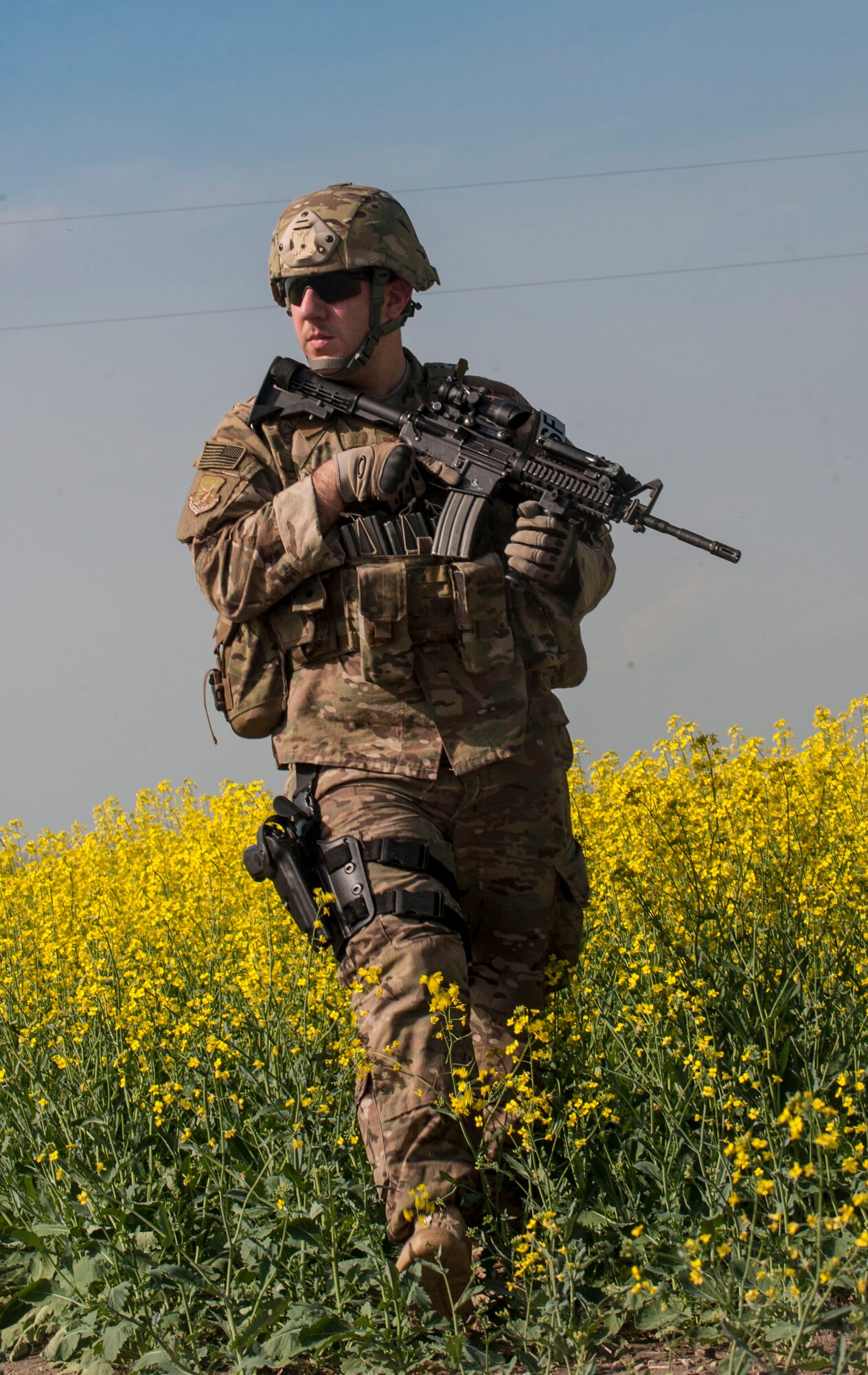 A 91st Missile Wing Security Forces Group member patrols through a canola field during an exercise area near Donnybrook, N.D., June 29, 2015. After suppressing personnel acting as simulated aggressors, Airmen participating in the exercise set up a secure perimeter and conducted thorough sweeps of the area. (U.S. Air Force photo/Senior Airman Stephanie Morris)