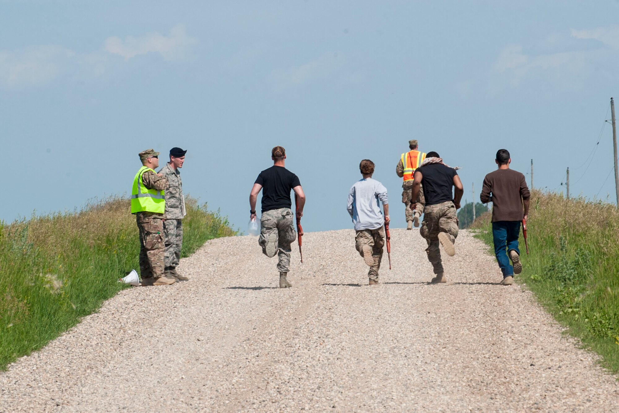 91st Missile Wing Security Forces Group members run toward an exercise area near Donnybrook, N.D., June 29, 2015. The group wore civilian clothes to distinguish themselves as simulated aggressors during the exercise. (U.S. Air Force photo/Senior Airman Stephanie Morris)