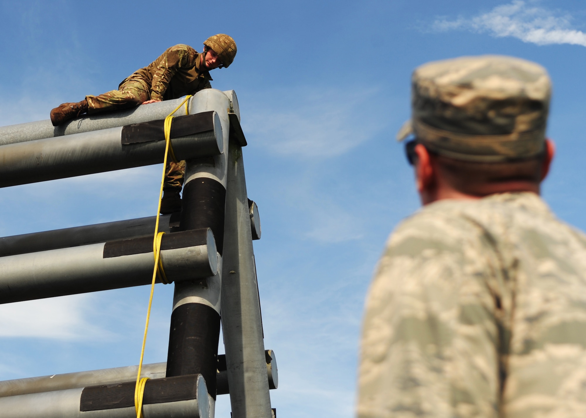 U.S. Air Force Maj. Kyle Johnson, Joint Communications Support Element operations officer, watches as British army Signaller Thomas Banks, 258th Signal Squadron communications operator, climbs over an obstacle at the Hillsborough County Sheriff’s Office Outdoor Shooting Range in Lithia, Fla., June 25, 2015. The confidence course tested the participant’s strength and endurance. (U.S. Air Force photo by Airman 1st Class Danielle Conde/Released)