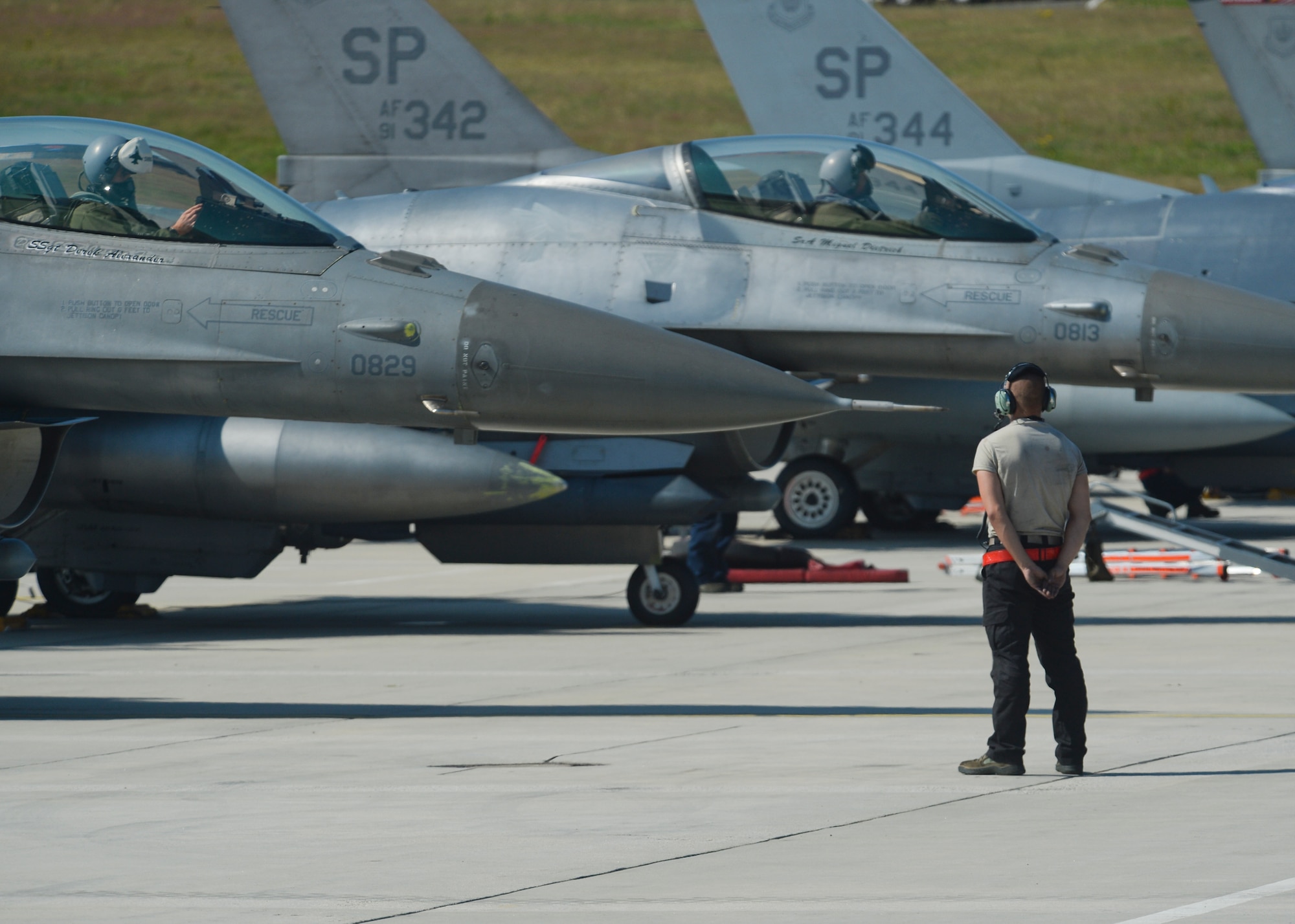 A U.S. Air Force crew chief assigned to the 52nd Aircraft Maintenance Squadron stands by as two F-16 Fighting Falcon fighter aircraft pilots assigned to the 480th Fighter Squadron prepare for taxiing from the flightline at Spangdahlem Air Base, Germany, July 6, 2015. The aircraft will participate in Red Flag, the U.S. Air Force’s premier air-to-air combat training exercise in Nellis Air Force Base, Nevada, July 13-31, 2015. (U.S. Air Force photo by Staff Sgt. Joe W. McFadden/Released)