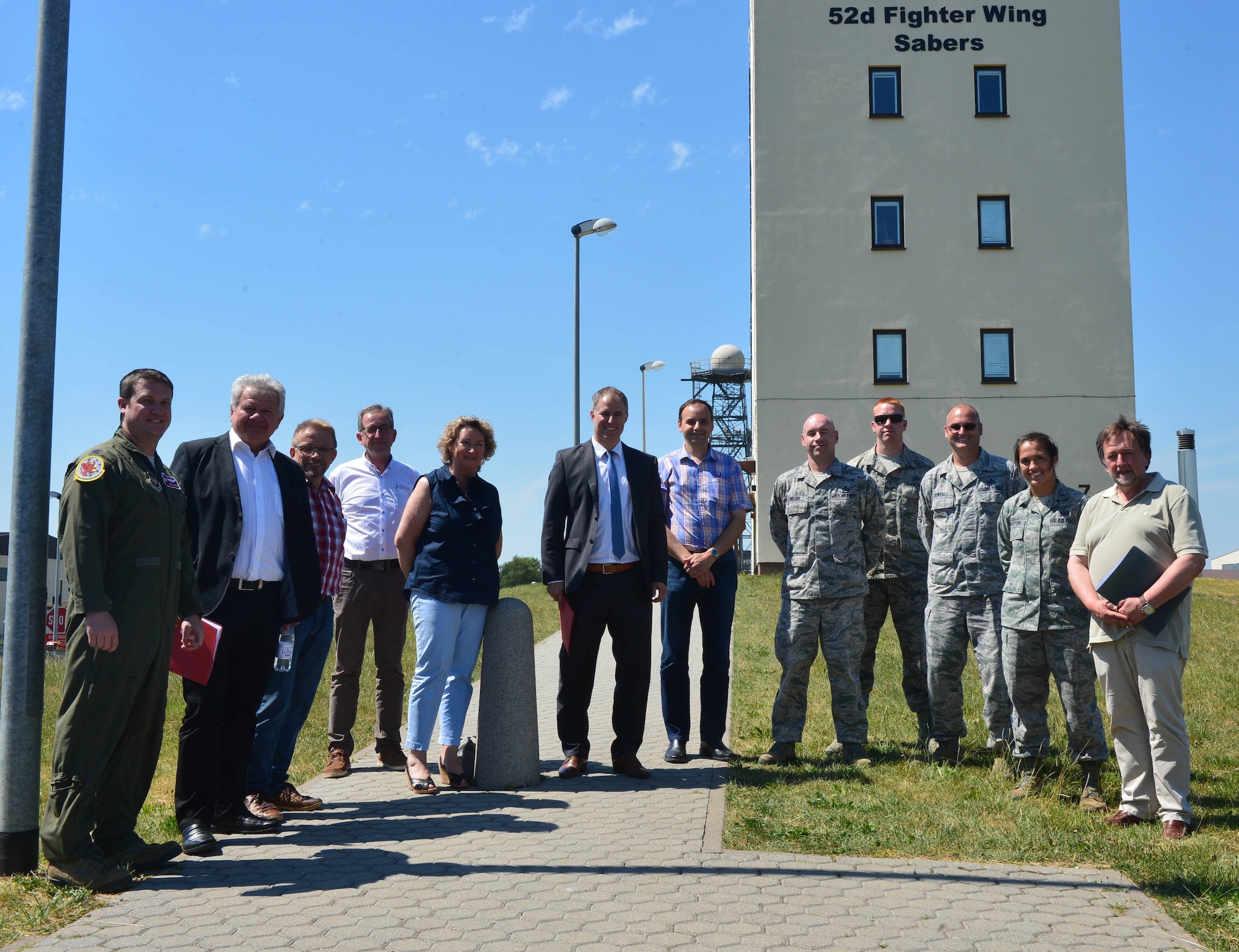 Members of the 52nd Fighter Wing stand with several local leaders during a base orientation tour outside the air control tower at Spangdahlem Air Base, Germany, July 1, 2015. The tour allowed the leaders to see the base and learn about current 52nd FW operations. (U.S. Air Force photo by 2nd Lt Meredith Mulvihill/Released)