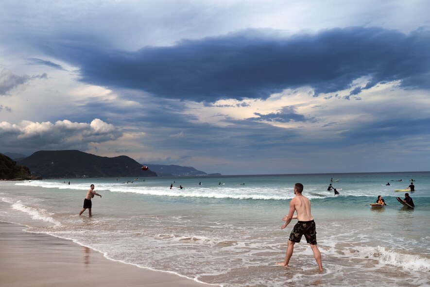 Senior Airman Patrick Cole tosses a football to Airman 1st Class Joshua Belford in the waters of Tadato Beach in Shimoda, Japan, June 27, 2015. The retreat allowed for Airmen to both learn to surf and build new relationships with other participants. (U.S. Air Force photo by Airman 1st Class Delano Scott/Released)