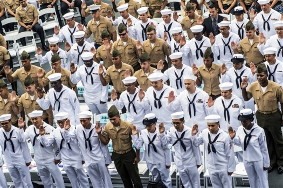 Sailors and Marines from the San Diego area raise their right hand during the oath of citizenship aboard the aircraft carrier museum USS Midway in San Diego, July 1, 2015. About 50 sailors and Marines from 22 countries became naturalized U.S. citizens during the ceremony.