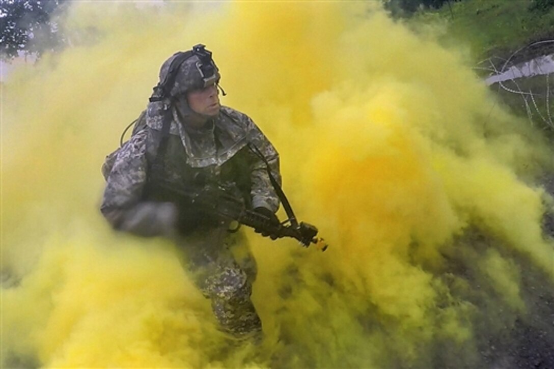 A soldier runs through smoke after placing a simulated explosive charge on an objective during integrated brigade training on Fort Drum, N.Y., June 24, 2015. The soldier is assigned to the Maine Army National Guard's 251st Engineer Company.
