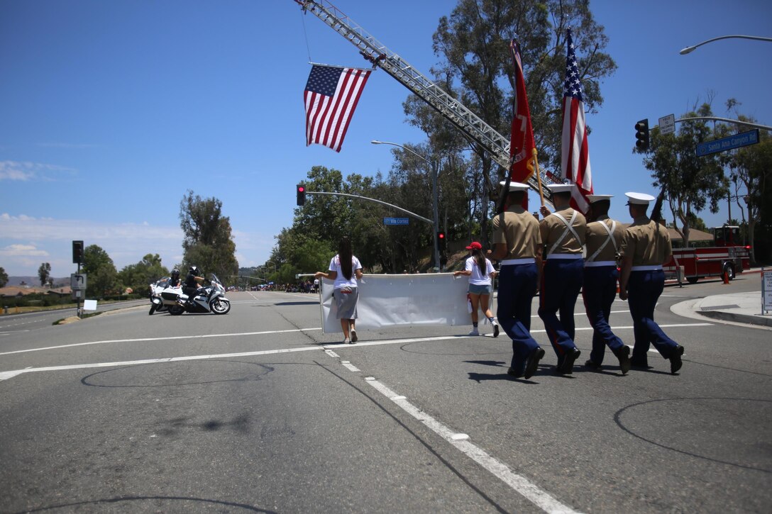 Marines from the 13th Marine Expeditionary Unit march alongside their adopted families in the city of Anaheim, Calif., July 4th, 2015. The Anaheim Marine Adoption Committee adopted the 13th MEU and provides aid in the form of baby baskets, care packages and homes to take refuge for the Marines who aren't able to return hom for the holidays.(U.S. Marine Corps photo by Lance Cpl. Alvin Pujols/Released)