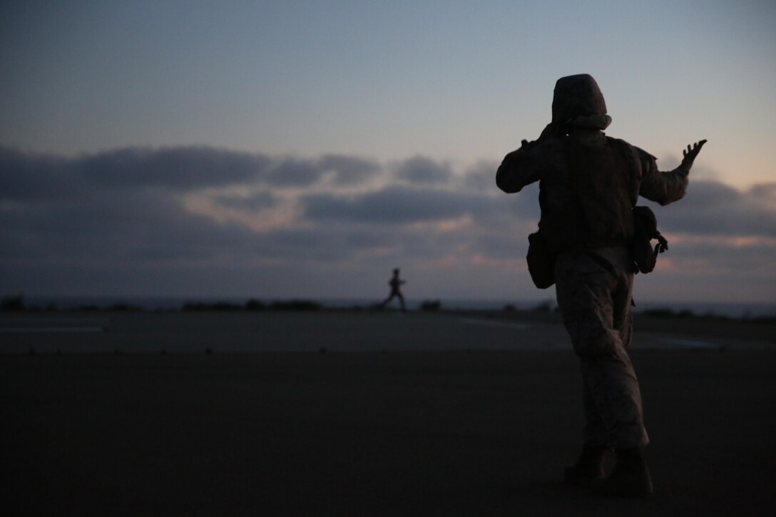 One Marine with Golf Company, Battalion Landing Team 2nd Battalion, 1st Marine Regiment directs others away from the landing area during nighttime fast-rope training on Marine Corps Base Camp Pendleton, California, July 2. The infantry Marines conducted fast-rope training with Marine Heavy Helicopter Squadron (HMH) 466. (U.S. Marine Corps photo by Sgt. Lillian/Released)